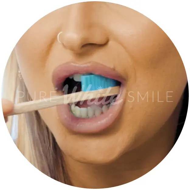 A client brushing her teeth with a Natura White toothbrush and fine-grit toothpaste as part of step 2 of the laser teeth whitening process, removing plaque and surface debris before treatment at Pure White Smile in Chorley.